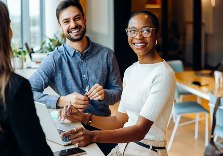 Trois employés discutent autour d'un ordinateur portable